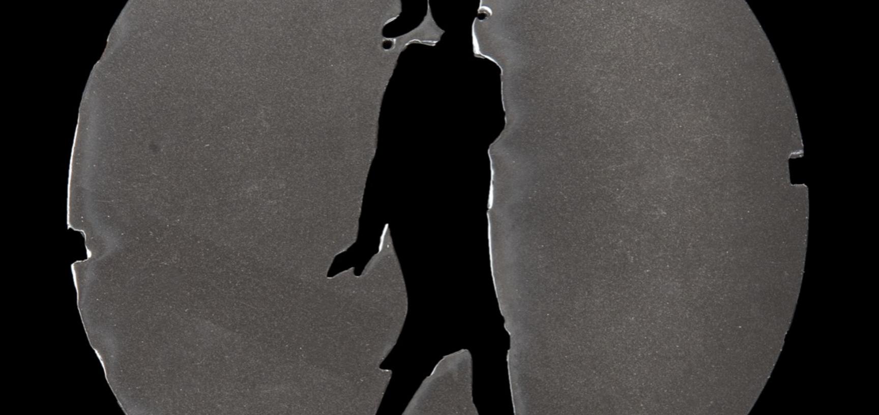 Circle of plastic with a cut-out figure in the shape of a person in a dress with a tall, formal hairstyle and high heels.