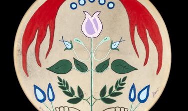 Circular drum of tanned hide with a stylised flower in the centre, leaves, and a red pattern at the top.