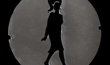 Circle of plastic with a cut-out figure in the shape of a person in a dress with a tall, formal hairstyle and high heels.